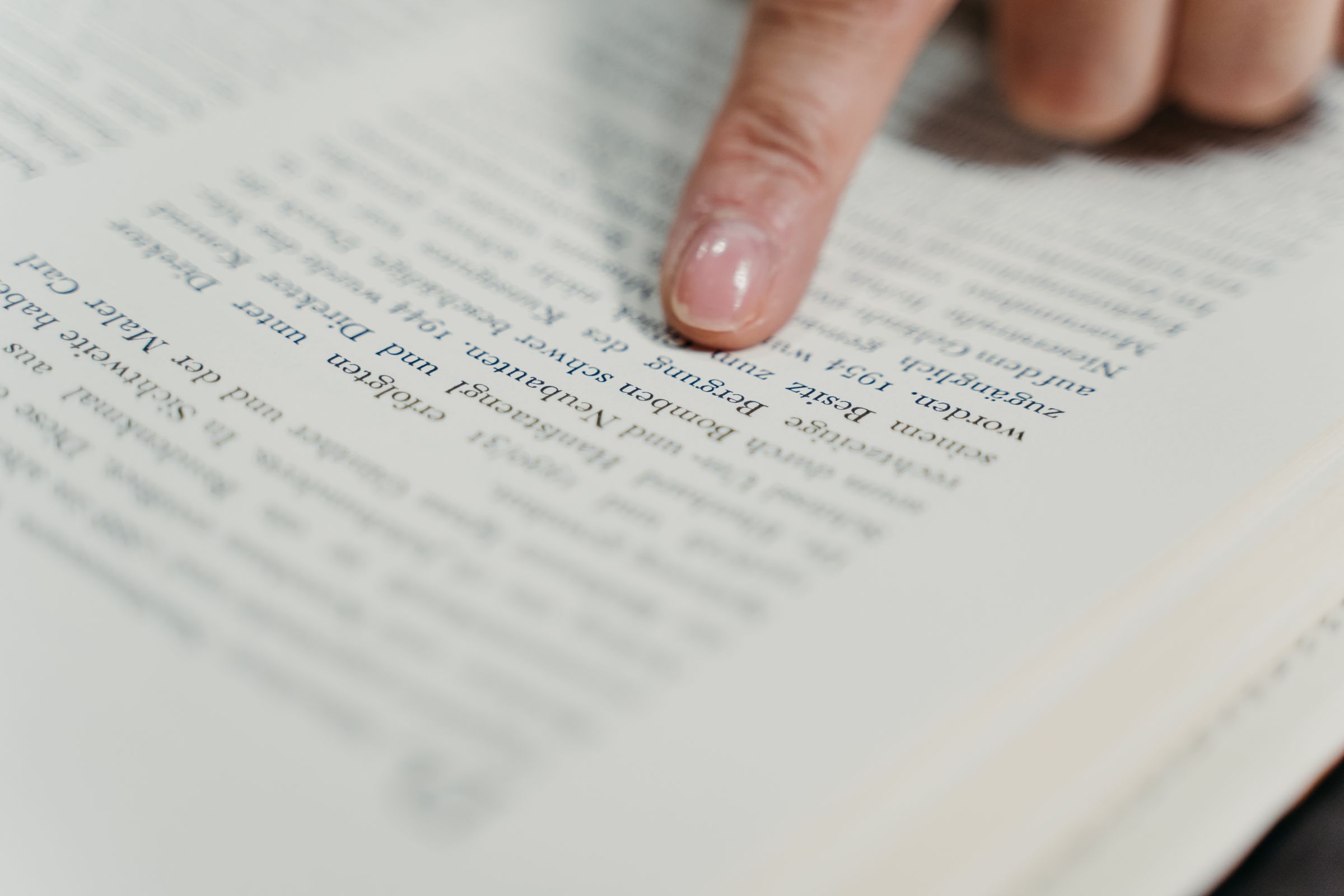 A finger following a line of text on the page of an open book