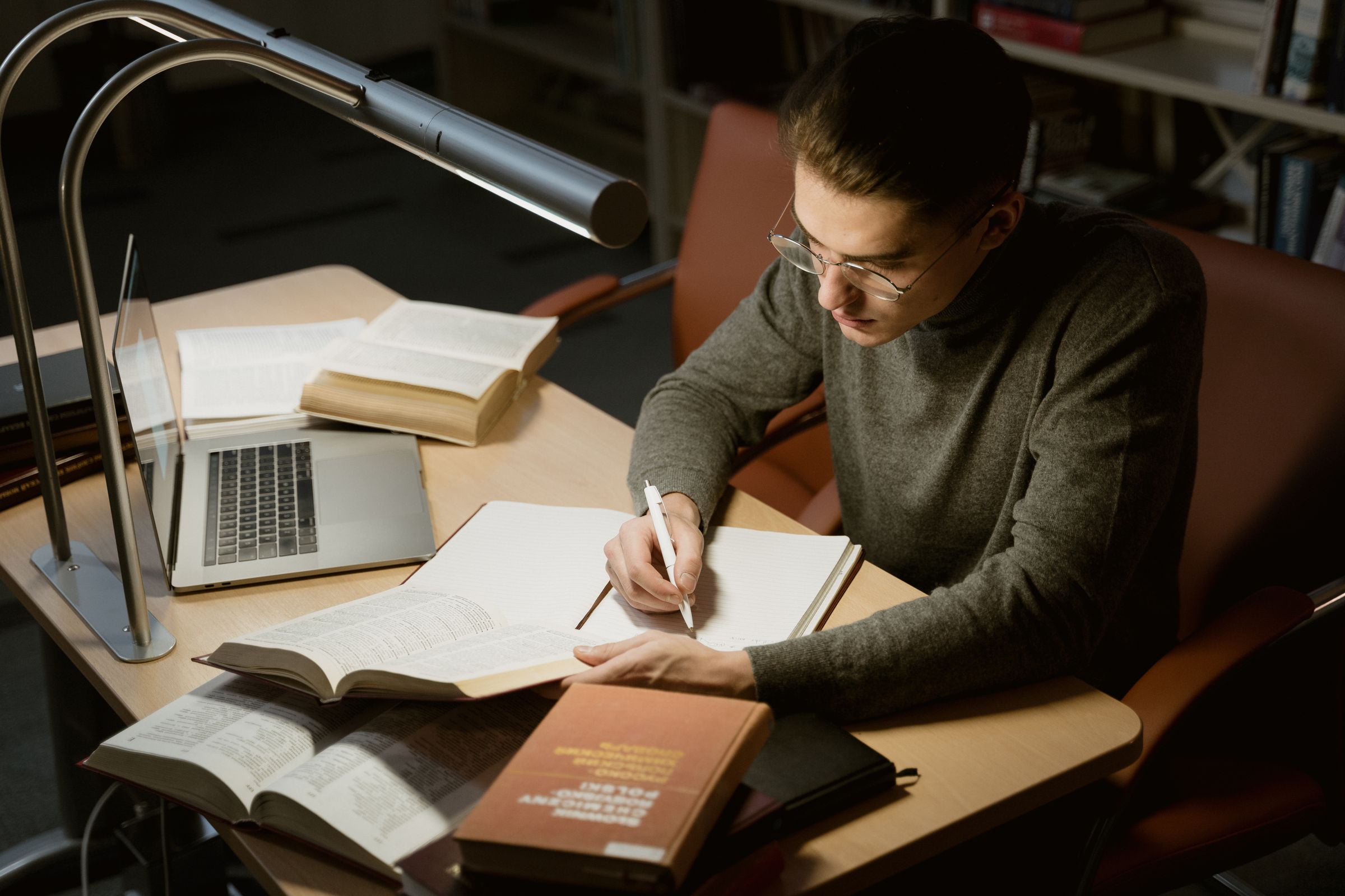 An early-career researcher reading under a library lamp