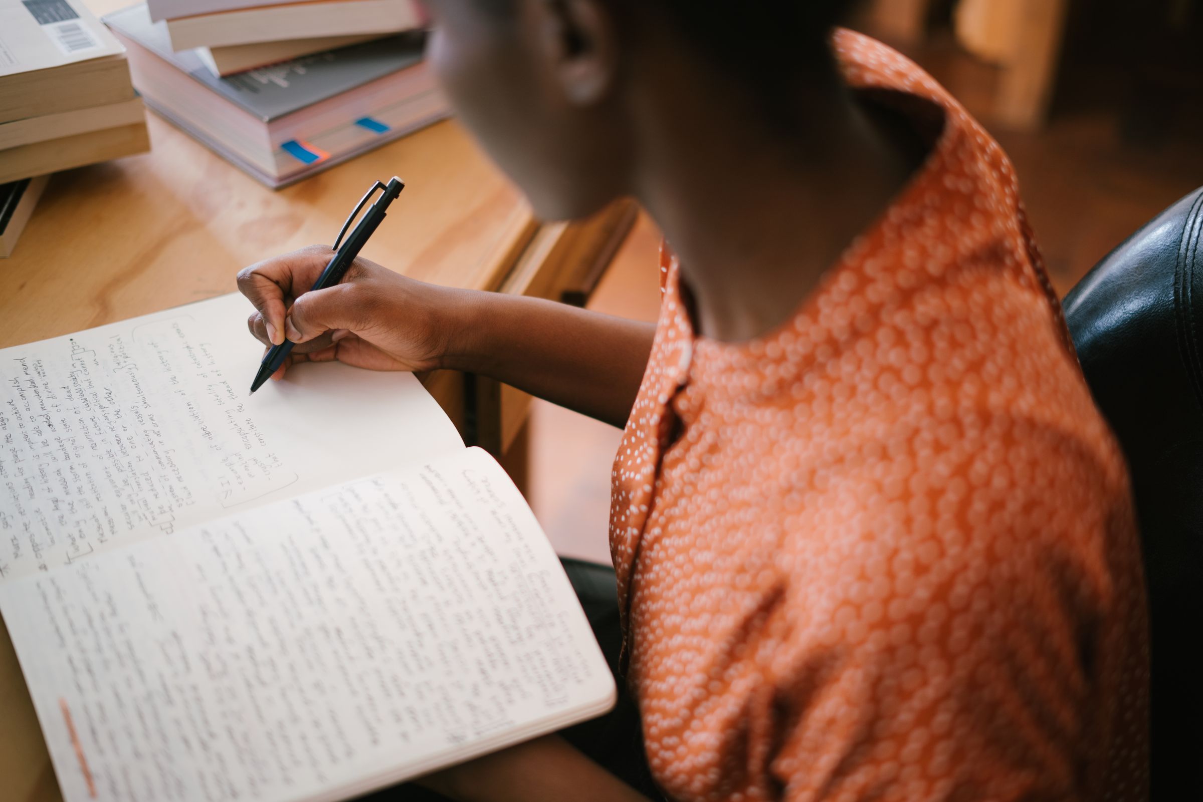 Writing notes in a notebook beside a laptop